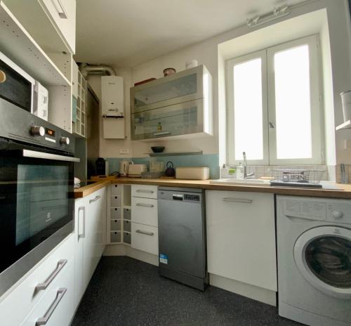 a kitchen with white cabinets and a washer and dryer at The Montpellier Escape-Duplex featuring a terraceconditioning in Montpellier