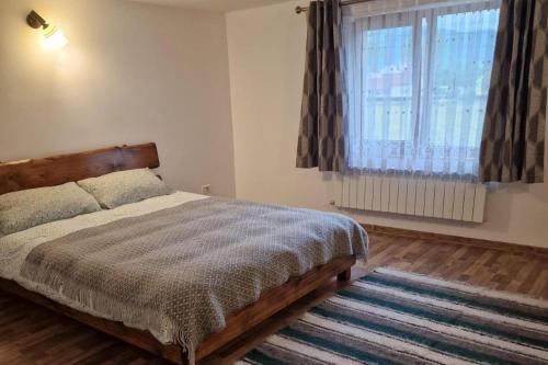 a bedroom with a bed and a window and a rug at Bucovina-MountainHouse-5Br-Fireplace-HotTub-WiFi in Suceviţa