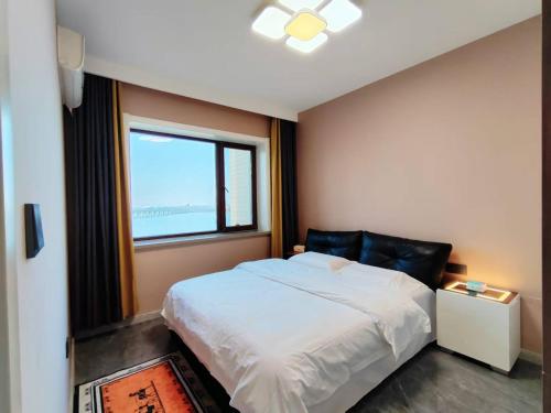 Un dormitorio con una cama blanca y una ventana. en Central Avenue Luxury River View Apartment, en Harbin