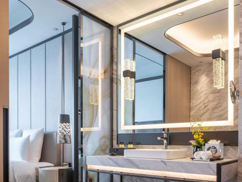 a bathroom with a sink and a large mirror at Pullman Suzhou Zhonghui in Suzhou
