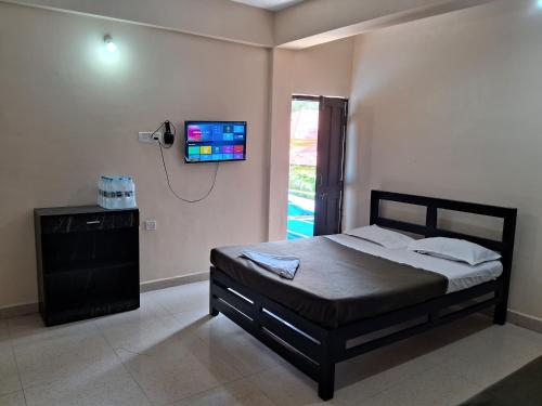 Un dormitorio con una cama y un televisor en la pared. en Calangute Pristine Guest House, en Calangute