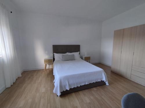 a bedroom with a white bed and a wooden floor at Casa da Nogueira in Paredes de Coura