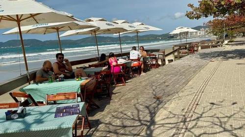 a group of people sitting at tables on the beach at Lindo Apartamento compartilhado vista MAR in Itapema