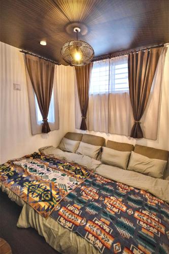 a large bed in a room with curtains at Dual Life House Koza in Okinawa City