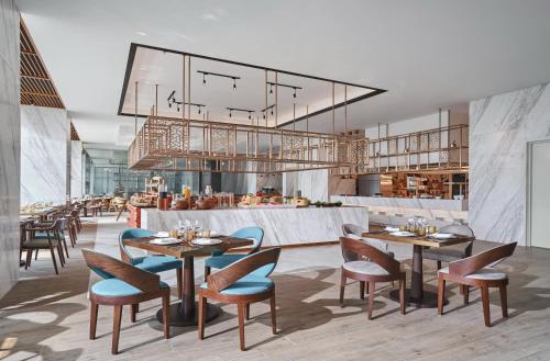 Un restaurante con mesas y sillas y un bar. en voco Ma Belle Danang by IHG, en Da Nang