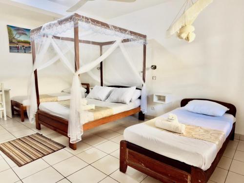 a bedroom with two beds and a canopy bed at Hôtel - Appartement meublé " LES FLOTS BLEU " in Antananarivo