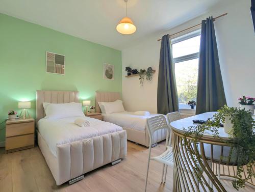 ein Schlafzimmer mit zwei Betten und einem Tisch und einem Fenster in der Unterkunft Charming 3-bed Home Near Centre Free Parking in York