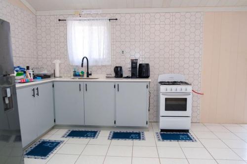 a kitchen with white cabinets and a sink and a stove at Nestled Vacation Home in Saint Johnʼs