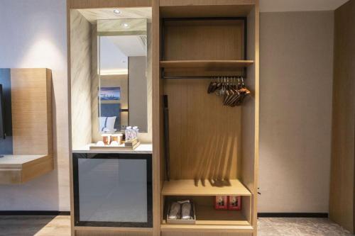 a kitchen with a wooden cabinet with a mirror at Guangzhou CHILLNOW Hotel in Guangzhou
