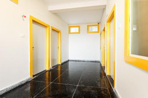 博帕尔Hotel O Kanha Stay的一条通往空房间的走廊，走廊尽头是黄色的门。