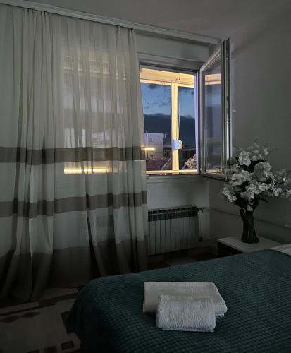a bedroom with a bed and a window with a vase of flowers at Down Town Apartment 2 in Gjilan