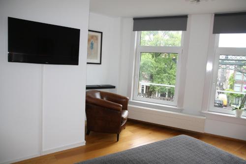 a living room with a chair and two windows at Bridge Inn in Amsterdam