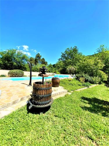 a fountain in the grass next to a swimming pool at Gîte et chambre d'hôtes LE MERCOIRE, piscine chauffée et jacuzzi in Aubenas