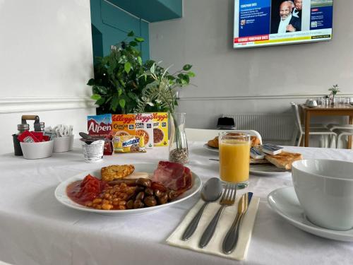 Una mesa blanca con un plato de comida y jugo de naranja. en Beach Hotel Torbay B&B, en Paignton