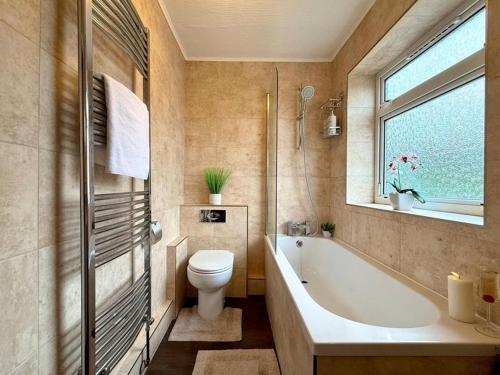 a bathroom with a tub and a toilet and a window at Bright & Lovely Apartment in Chelmsford in Chelmsford