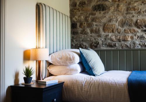 a bed with pillows and a table with a lamp at Neddy Meadow in Grinton