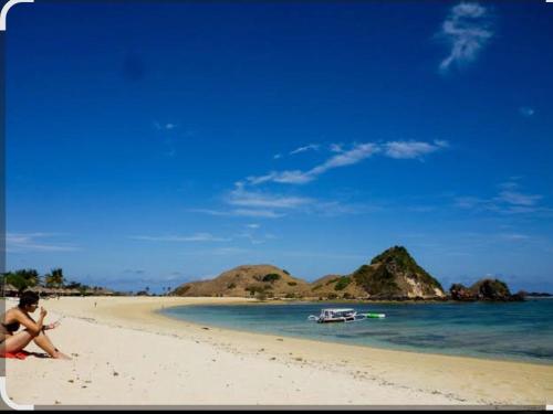 a person sitting on a sandy beach near the ocean at Sasak Lombok Bungalow in Kuta Lombok
