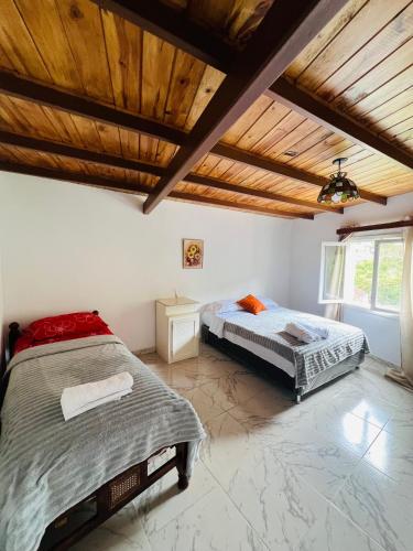 2 bedden in een slaapkamer met een houten plafond bij Cabaña jenny in Tovar