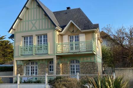 een groot huis met een balkon erbovenop bij Villa Bellevue - Anglo-Norman seafront house in Ouistreham