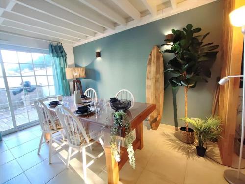 een eetkamer met een tafel en stoelen en een surfplank bij Cosy Villa by sea ! - two terraces in Ouistreham