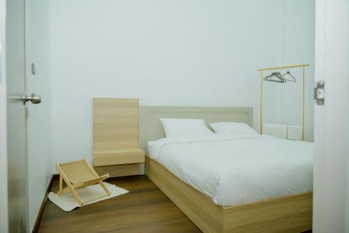 Un dormitorio con una cama blanca y un taburete de madera. en B2 Romance Resort บีสแควร์ โรแมนซ์ รีสอร์ท, en Sathani Phu Khao Lat