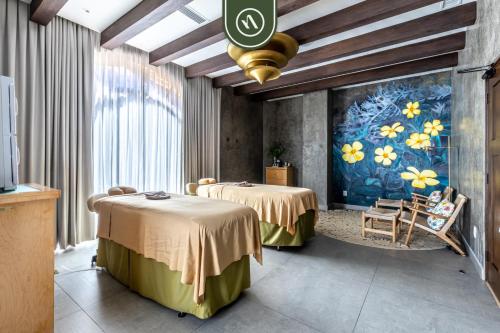 two beds in a room with a painting on the wall at Amazing House with Private Terrace - Private Pool in El Tule