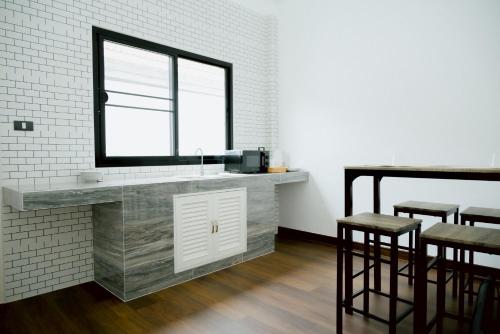 a kitchen with a sink and a window and stools at B2 Romance Resort บีสแควร์ โรแมนซ์ รีสอร์ท in Sathani Phu Khao Lat