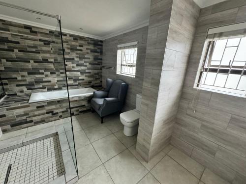 a bathroom with a tub and a chair and a shower at Da Silva Residence in George