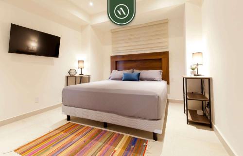 een slaapkamer met een groot bed en een tv bij Cozy Apt with Private Terrace - Pool - King Beds in Nuevo Vallarta 