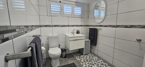 a bathroom with a toilet and a sink and a mirror at Salt & Soul Stay in Gordonʼs Bay