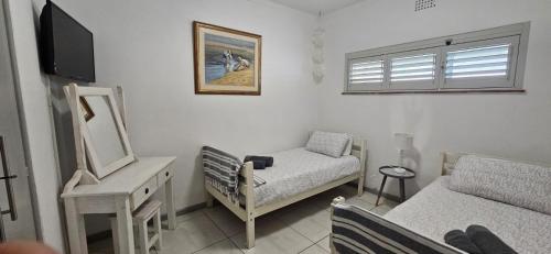a living room with a bed and a chair and a mirror at Salt & Soul Stay in Gordonʼs Bay