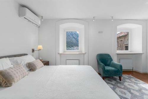 a white bedroom with a bed and a green chair at Sponza House in Trstenik