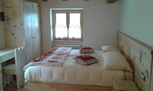 a bedroom with a bed with pillows and a window at Restor Natura Malga Mondent in Pracorno di Rabbi