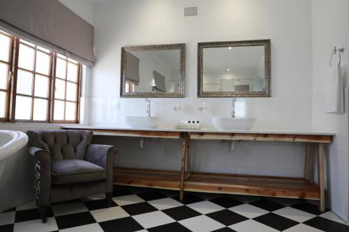 a bathroom with two sinks and a chair and mirrors at Old Posthouse Guest Accommodation in Ladismith