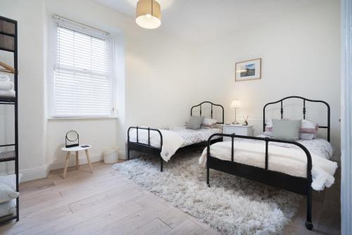 two beds in a white room with a rug at Three Bridges - 1-Mile from Ulverston Town Centre in Ulverston