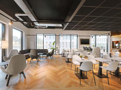 a waiting room with tables and chairs and windows at B&B HOTEL Berlin Airport-Nord in Berlin