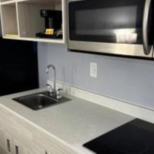 a kitchen counter with a sink and a microwave at Suburban Studios Christiansburg - Blacksburg in Christiansburg