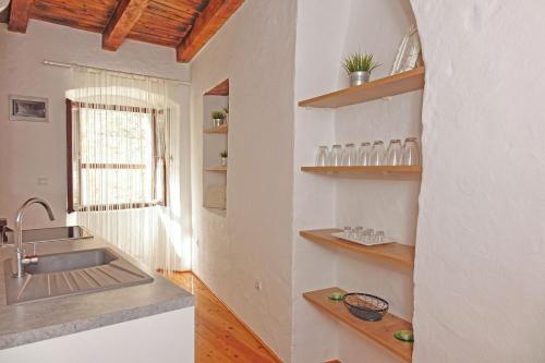 a kitchen with a sink and wooden shelves at Holiday home Castelier in Vodnjan