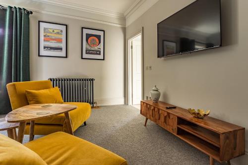 a living room with a couch and a tv on the wall at Dacre House in Gilsland