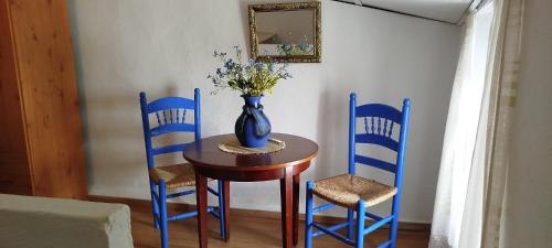 ein Tisch mit blauen Stühlen und einer Vase mit Blumen darauf in der Unterkunft Casa Rural Galaroza La Bella in Galaroza
