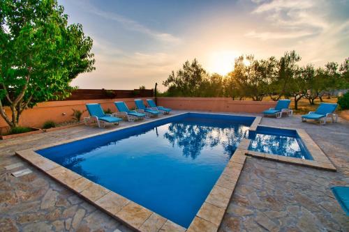 a swimming pool with blue lounge chairs and a swimming pool at MY DALMATIA - Apartment Visocane with private pool in Visočane