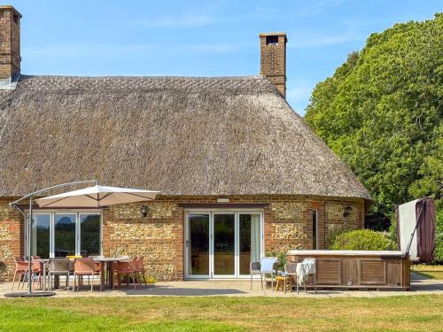 a stone house with a thatched roof with tables and chairs at Greenwood Grange in Dorchester
