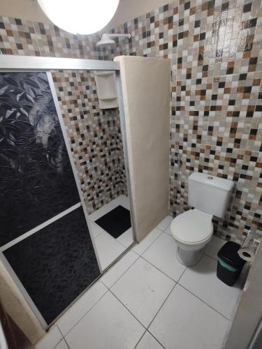 a small bathroom with a toilet and a shower at Chalé Maison Blanche in Maracanã