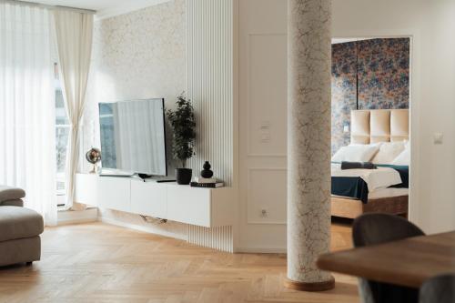 a white bedroom with a bed and a tv in it at Apartma Tyrseva in Maribor