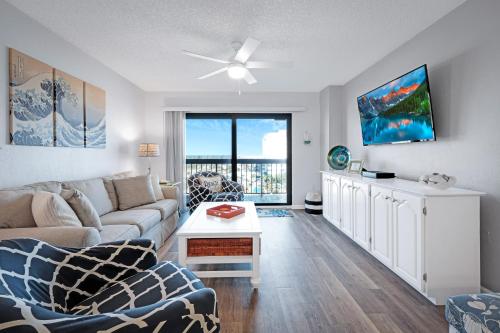 a living room with a couch and a table at Oceanfront with great beach views from all rooms & balcony, heated pool, and garage in Ormond-by-the-Sea