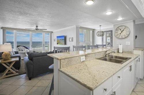 a kitchen and living room with a clock on the wall at New listing! Direct oceanfront condo with a balcony, heated pool, and tennis court in Bottle Island