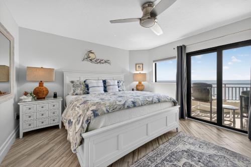 a white bedroom with a bed and a balcony at New listing! Direct oceanfront with private balcony, pool, and hot tub in Bottle Island