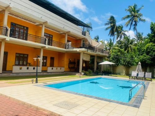 una casa con piscina delante de un edificio en Woodnest Saayoo Resort, en Negombo