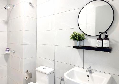 a white bathroom with a sink and a mirror at Amber Cove l Luxury Suites 2BR l 6-9pax l GamesRoom l City Centre l Jonker St l Encore l Playground by Jay Stay in Melaka