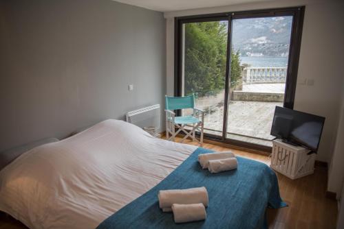 a bedroom with a bed and a view of a beach at Le Panoramique Rivage - Terrasse privative in Duingt